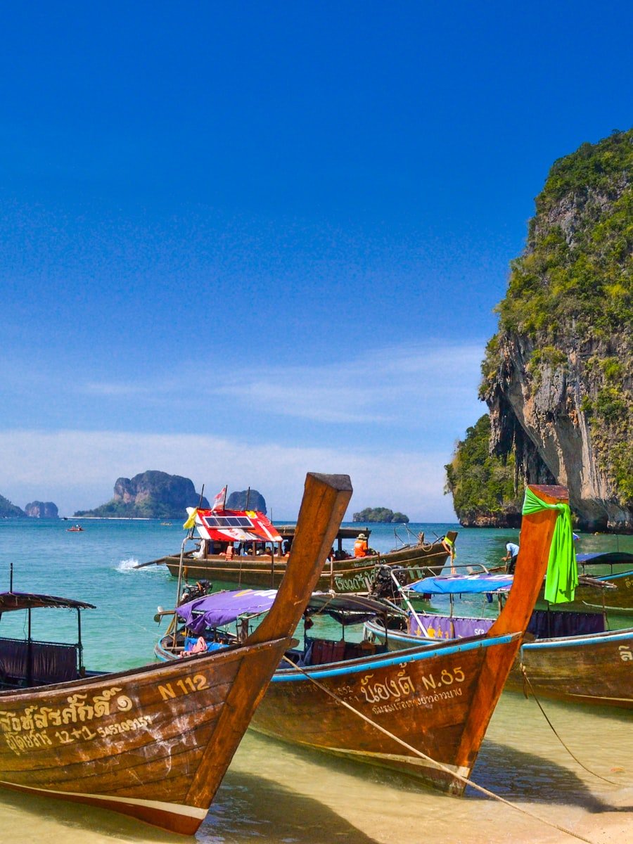 Long-tail boat on turquoise water beneath limestone cliffs in southern Thailand